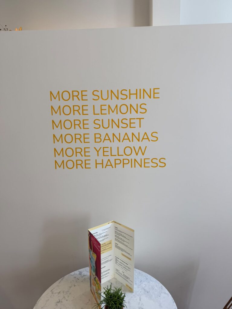 Gele wandtekst met More Sunshine, More Lemons en More Happiness bij Happyness Café