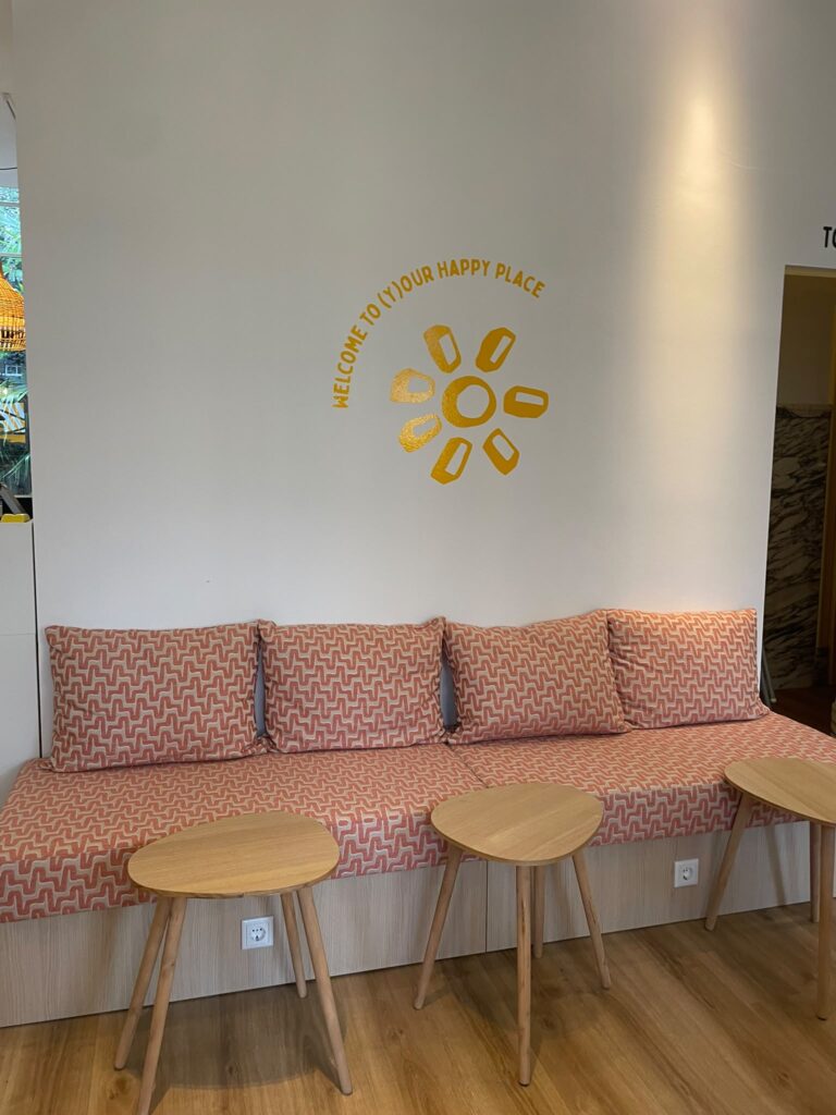 Gele wandbelettering Welcome to (Y)our Happy Place bij Happyness Café in Haarlem