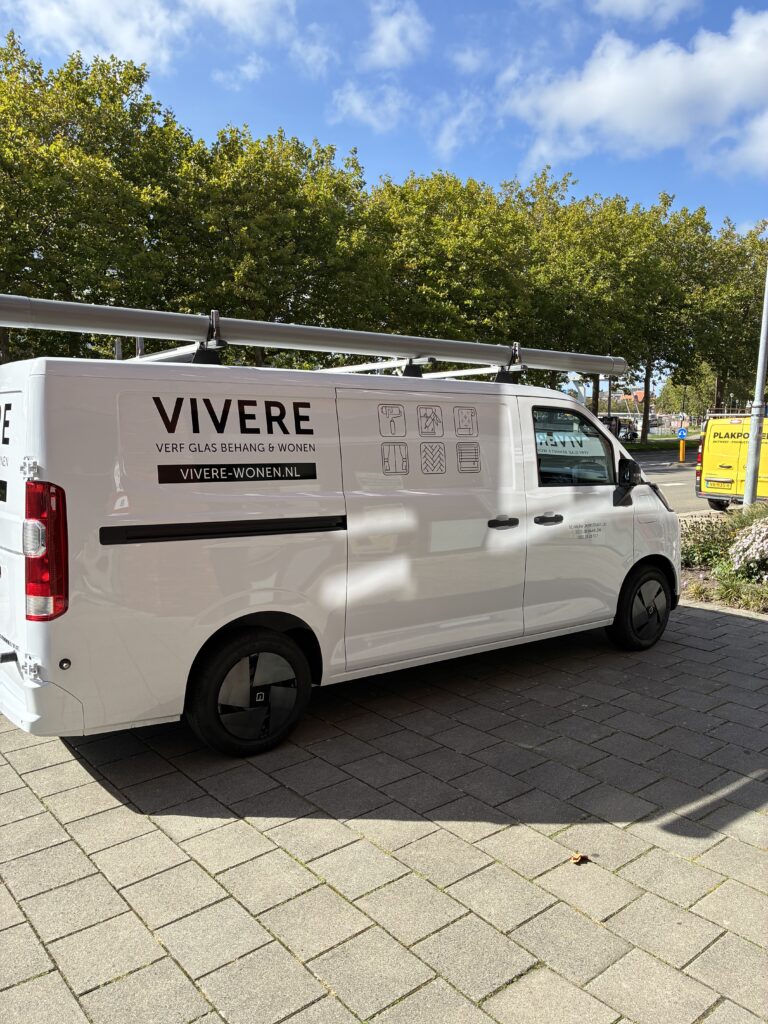 Zijaanzicht van de beletterde Vivere bedrijfsbus met logo, webadres en producticonen