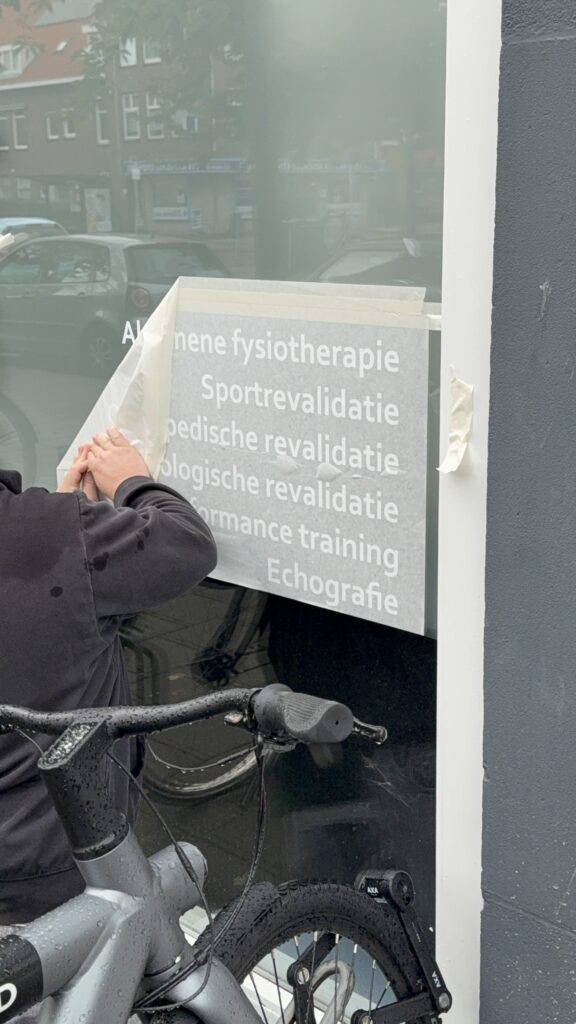 Montage van witte raambelettering op het raam van Fysiotherapie Eksterlaan