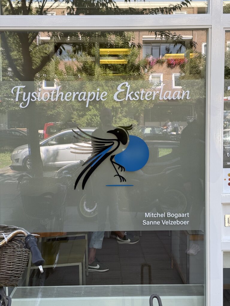 Raam van Fysiotherapie Eksterlaan met praktijknaam, vogelbeeldmerk en melkglasfolie