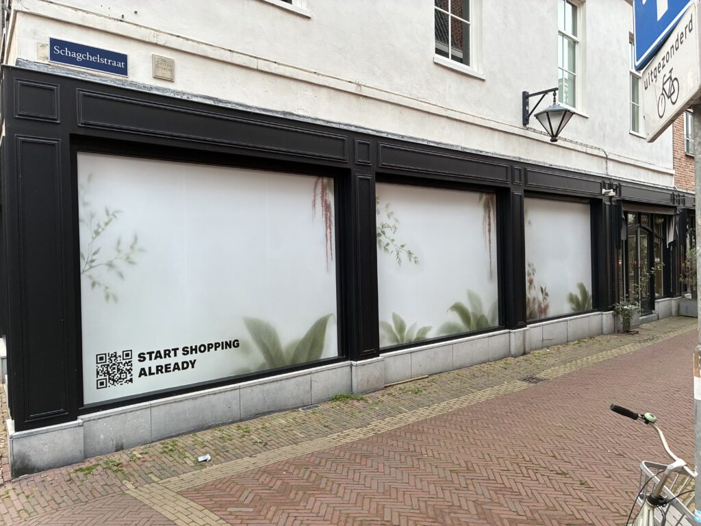 Zijgevel van Japan TKY in Haarlem met tijdelijke bedrukte etalagefolie, botanische prints en een QR-code.